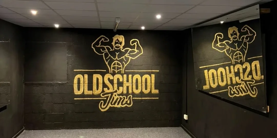 The posing room at Old School Jim's Telford: black walls painted with the gold Old School Jim's logo, reflected in a long mirror